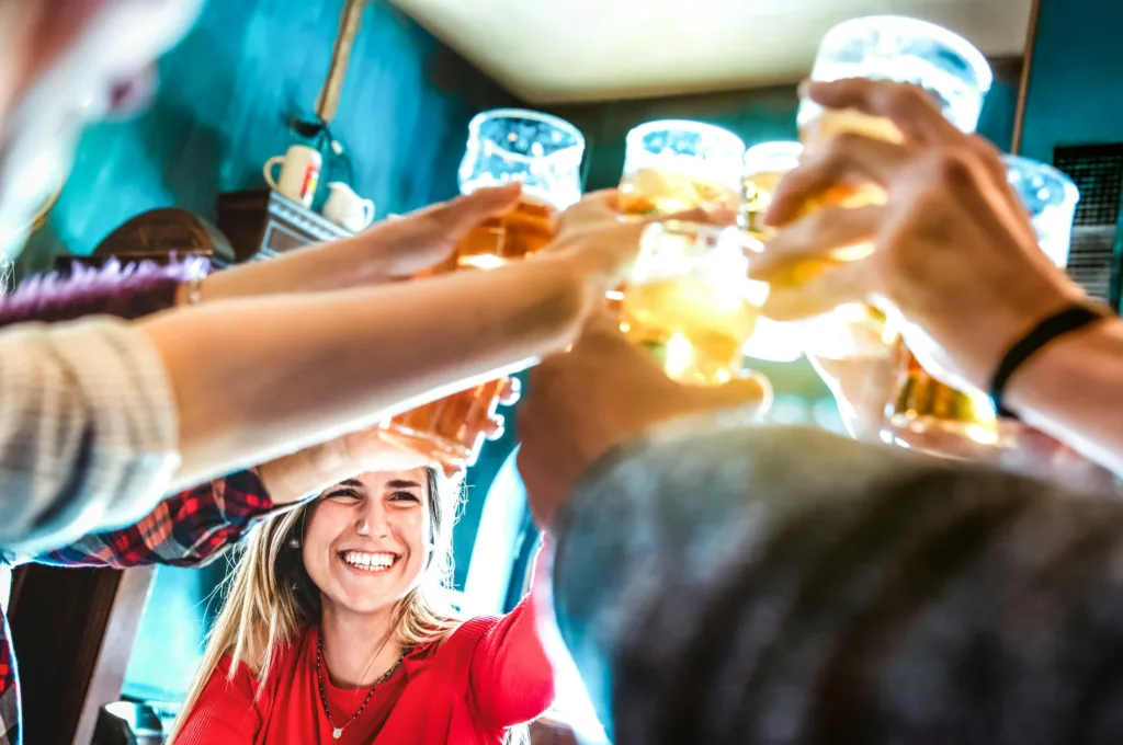 Friends drinking and toasting beer at brewery bar restaurant
